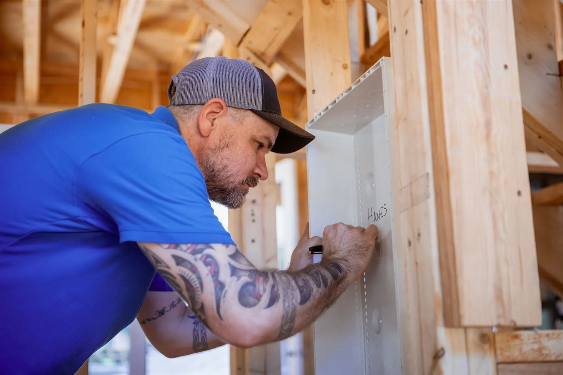 A technician working inside a structured-wiring panel on a framed wall.