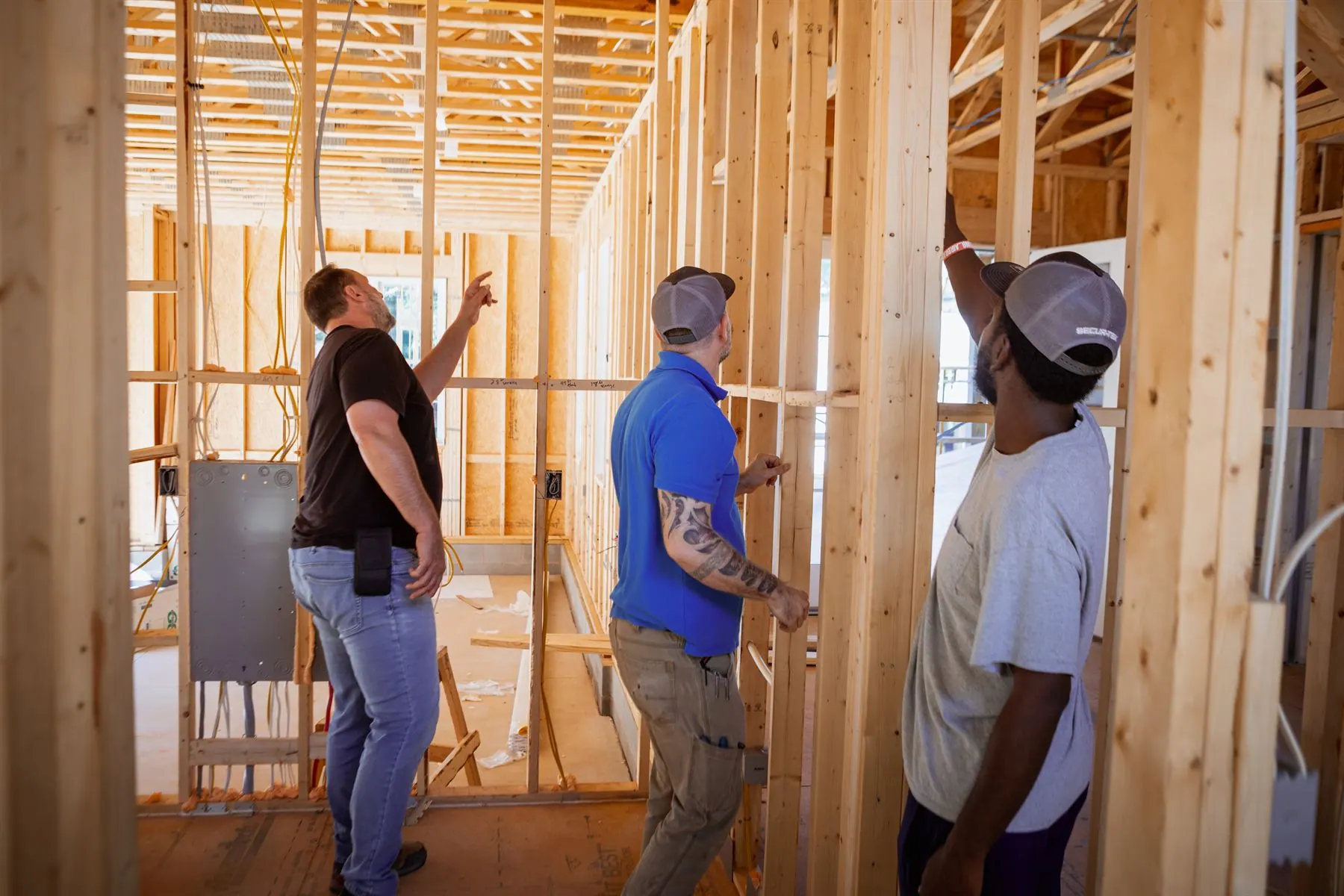 The crew walking a framed house on a pre-wire, pointing out the runs.